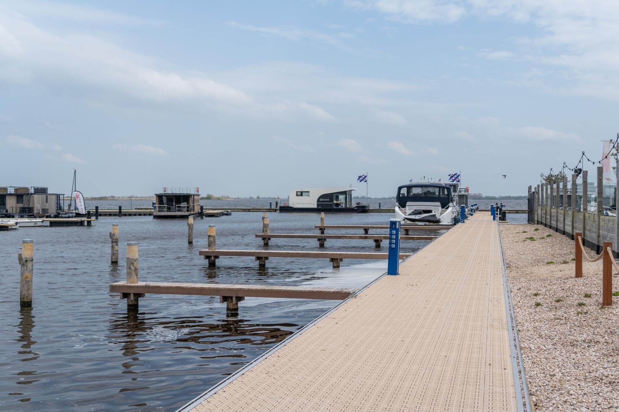 A waterfront dock with boats, a covered area, and a paved walkway.