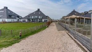 Un chemin de gravier mène à une rangée de maisons modernes, dotées de toits inclinés et de grandes fenêtres.