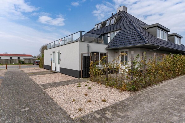 Una casa moderna a due piani con un balcone, un garage e un vialetto in ghiaia.