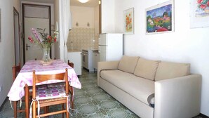 A compact living space with a dining area, a sofa, and a kitchenette. - Apartment in Caorle near Adriatic Beach (Caorle (VE))
