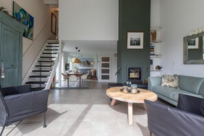 A spacious living area with a staircase, a dining table, and a sofa.