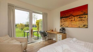 A hotel room with a bed, a desk, a chair, and a large window. - Holiday Home in Nieuwvliet near the Beach (Nieuwvliet)