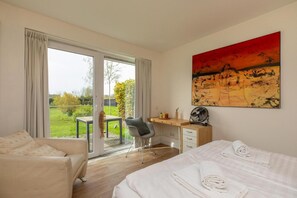 A hotel room with a bed, a desk, a chair, and a large window. - Holiday Home in Nieuwvliet near the Beach (Nieuwvliet)