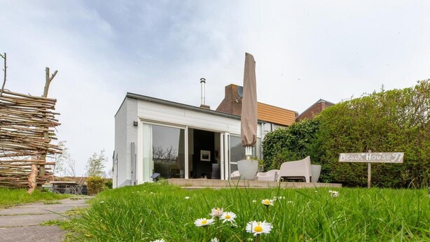 A modern house with a covered outdoor seating area, a garden with daisies, and a sign reading 'Beach House 97'. - Holiday Home in Nieuwvliet near the Beach (Nieuwvliet)