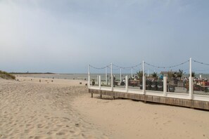 A beach with a wooden walkway and a glass enclosure with the word 'WEST' on it.