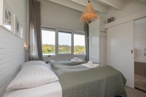 Un dormitorio con dos camas, una ventana que da a una obra en construcción y una lámpara colgante.