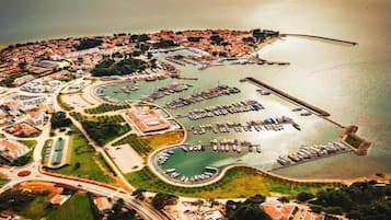 An aerial view of a coastal town with a marina, residential areas, and a roundabout.