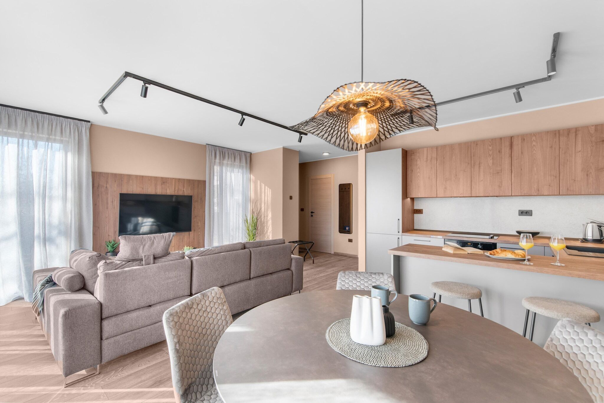 A modern living room with a sofa, a dining table, and a kitchen area with wooden cabinets and a countertop.
