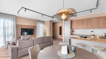A modern living room with a sofa, a dining table, and a kitchen area with wooden cabinets and a countertop.