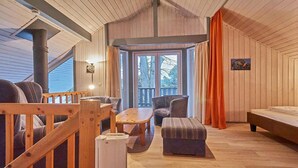 Indretning i en hyggelig hytte med trægulv, sofa, bord og bænk.