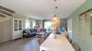 A spacious living area with a dining table, sofas, and a television.