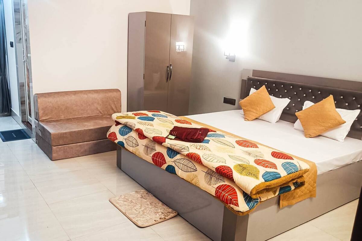 A hotel room with a bed, a sofa, a wardrobe, and a view of the outside.