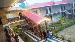 A multi-level building with a staircase, outdoor seating area, and potted plants. - Nature Green Resort (Mal)