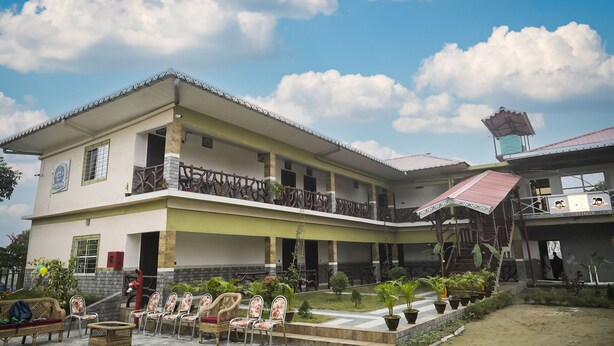 A two-story building with a balcony, outdoor seating, and potted plants. - Nature Green Resort (Mal)