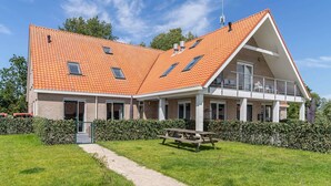 A two-story building with a sloped roof, a covered balcony, and a gravel path leading to the entrance. - Holiday Home in Nes near Vleijen Area (Nes)