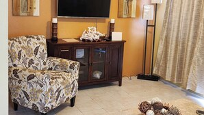 A living room with a sofa, a TV, a cabinet, and decorative wall art.