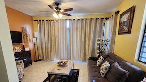A living room with a sofa, a coffee table, a TV, and curtains.