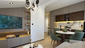 A modern living room with a marble coffee table, a painting, and a unique pendant light.