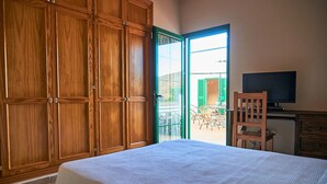 A bedroom with a bed, wooden wardrobe, a television, and a chair.