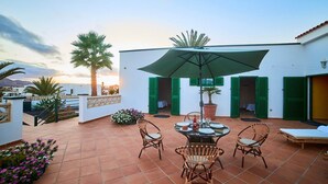 A terrace with a table and chairs, a large umbrella, and a potted plant.