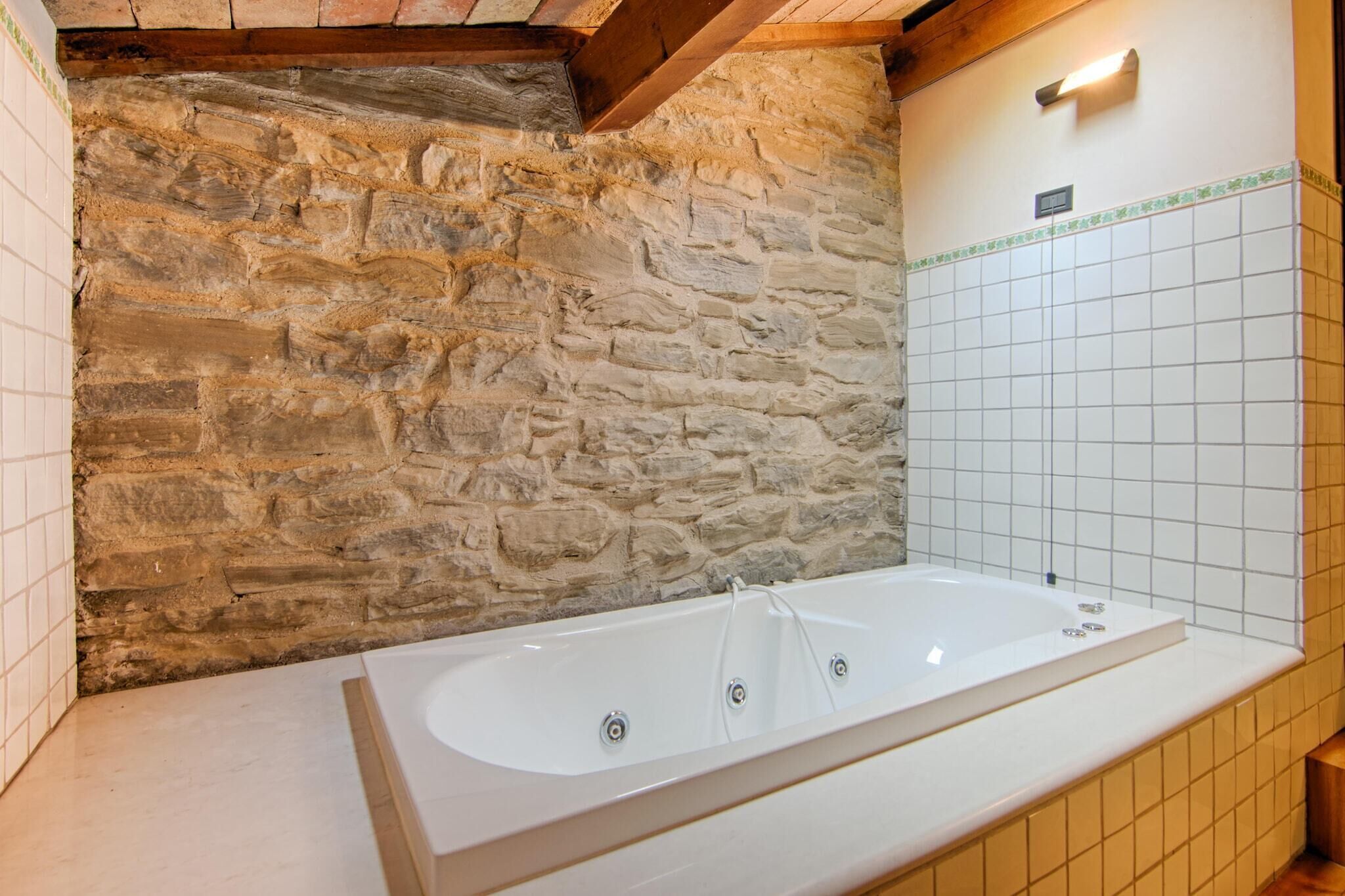 Une salle de bain avec un mur en pierre, une baignoire blanche et des murs recouverts de carreaux.