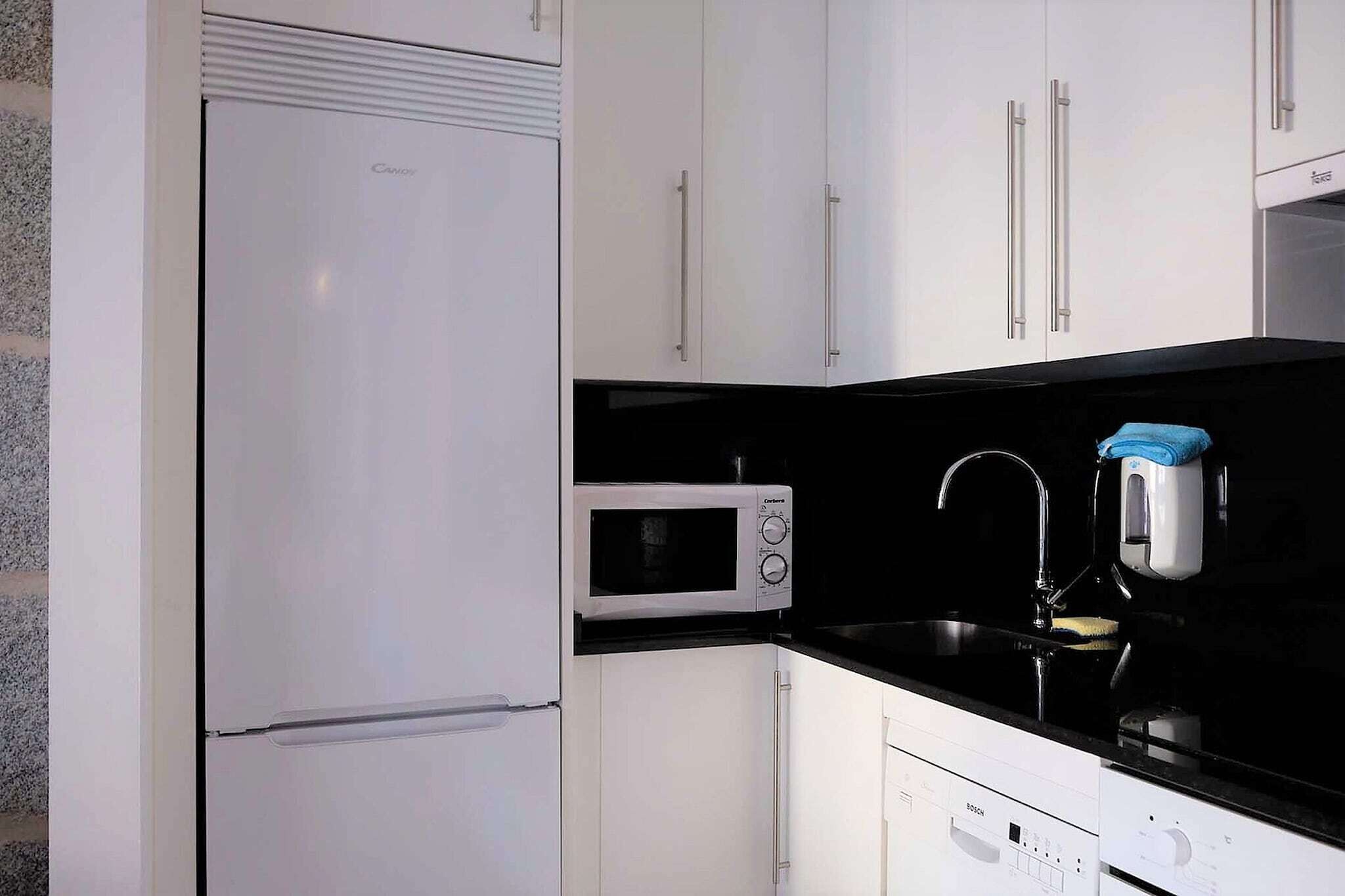 Una cucina compatta con frigorifero, forno a microonde e lavastoviglie.