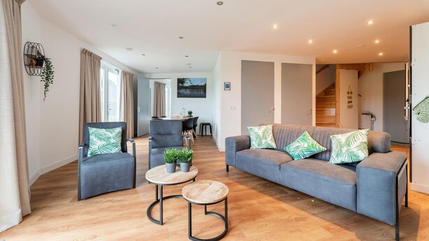 A modern living room with a grey sofa, two armchairs, and a coffee table.