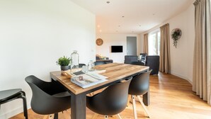 A modern dining area with a wooden table, black chairs, and a potted plant.