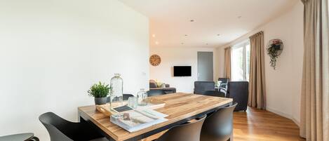 Un comedor moderno con una mesa de madera, sillas negras y una planta en maceta.