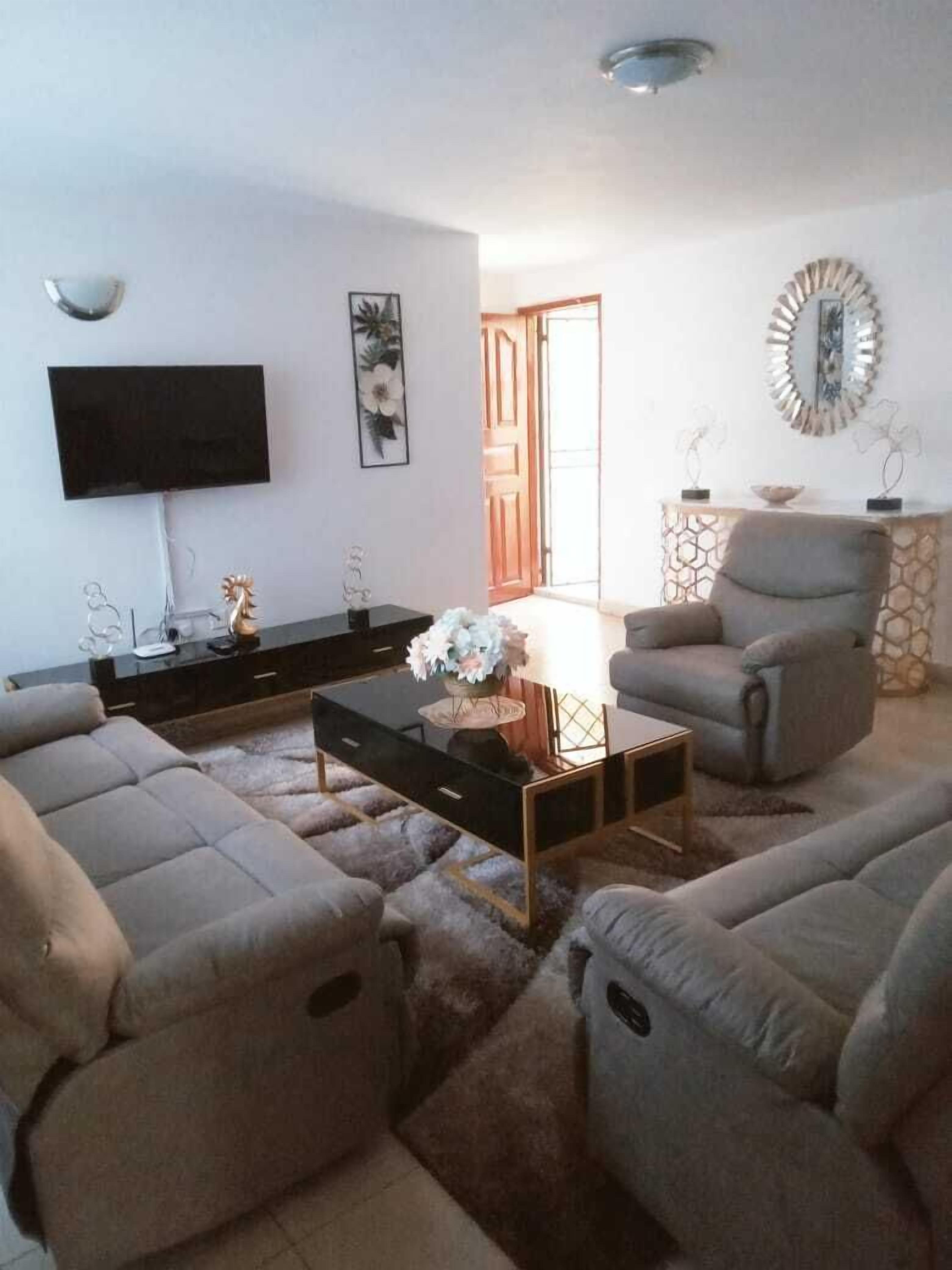 Sala de estar com sofá, mesa de centro, televisão e objetos decorativos.