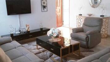 Sala de estar com sofá, mesa de centro, televisão e objetos decorativos.