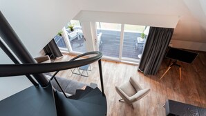 Un saló modern amb escala, televisió i vistes a la terrassa exterior.