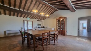 A spacious kitchen with a large island, wooden ceiling beams, and a built-in cabinet.