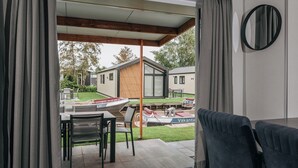 A modern room with a sliding glass door leading to a patio area. - Fenced Garden Family Chalet (Giethoorn)