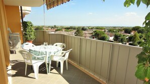 Ein Balkon mit Tisch und Stühlen, einem Blumentopf und Blick auf eine Wohngegend.