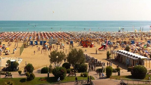 Ein überfüllter Strand mit vielen Sonnenschirmen und Menschen.