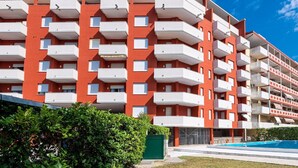 A multi-story residential building with balconies, a swimming pool, and a well-maintained garden area. - Holiday Home in Caorle near Spiaggia Tartaruga (Porto Santa Margherita (VE))