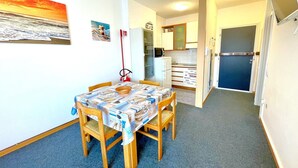 A compact kitchen with a refrigerator, microwave, and a small dining area with a table and chairs. - Holiday Home in Caorle near Spiaggia Tartaruga (Porto Santa Margherita (VE))