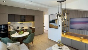 Eine moderne Küche mit integrierten Geräten, ein Essbereich mit rundem Tisch und Stühlen sowie eine Wohnbereich mit Sofa und Couchtisch.