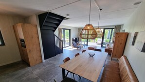 A modern interior with a wooden dining table, chairs, a sofa, and a staircase. - Water Villa in Balk with Private Jetty (Balk)