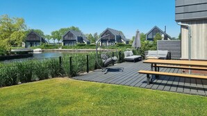 A deck with outdoor seating, a water feature, and modern buildings in the background. - Water Villa in Balk with Private Jetty (Balk)