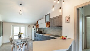 A modern kitchen with a large island, built-in appliances, and pendant lighting. - Country escape in Matelica (Matelica)