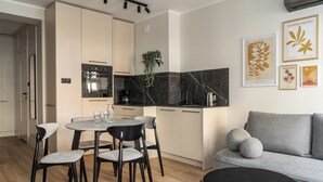 A modern kitchen with a dining area, a sofa, and artwork on the wall. - RentPlanet - Apartament Szczytnicka (Wroclaw)