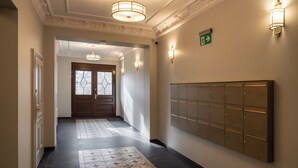 A hallway with patterned floor tiles, a wall-mounted locker system, and a door with frosted glass panels. - RentPlanet - Apartament Szczytnicka (Wroclaw)