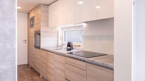 A modern kitchen with wooden cabinets, a built-in oven, a microwave, and a window above the sink. - Chalet in Kötschach near Ski Area Vorhegg (Kötschach-Mauthen)