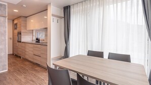 A modern kitchen with wooden cabinets, a built-in oven, and a microwave. There is a dining area with a wooden table and chairs. - Chalet in Kötschach near Ski Area Vorhegg (Kötschach-Mauthen)