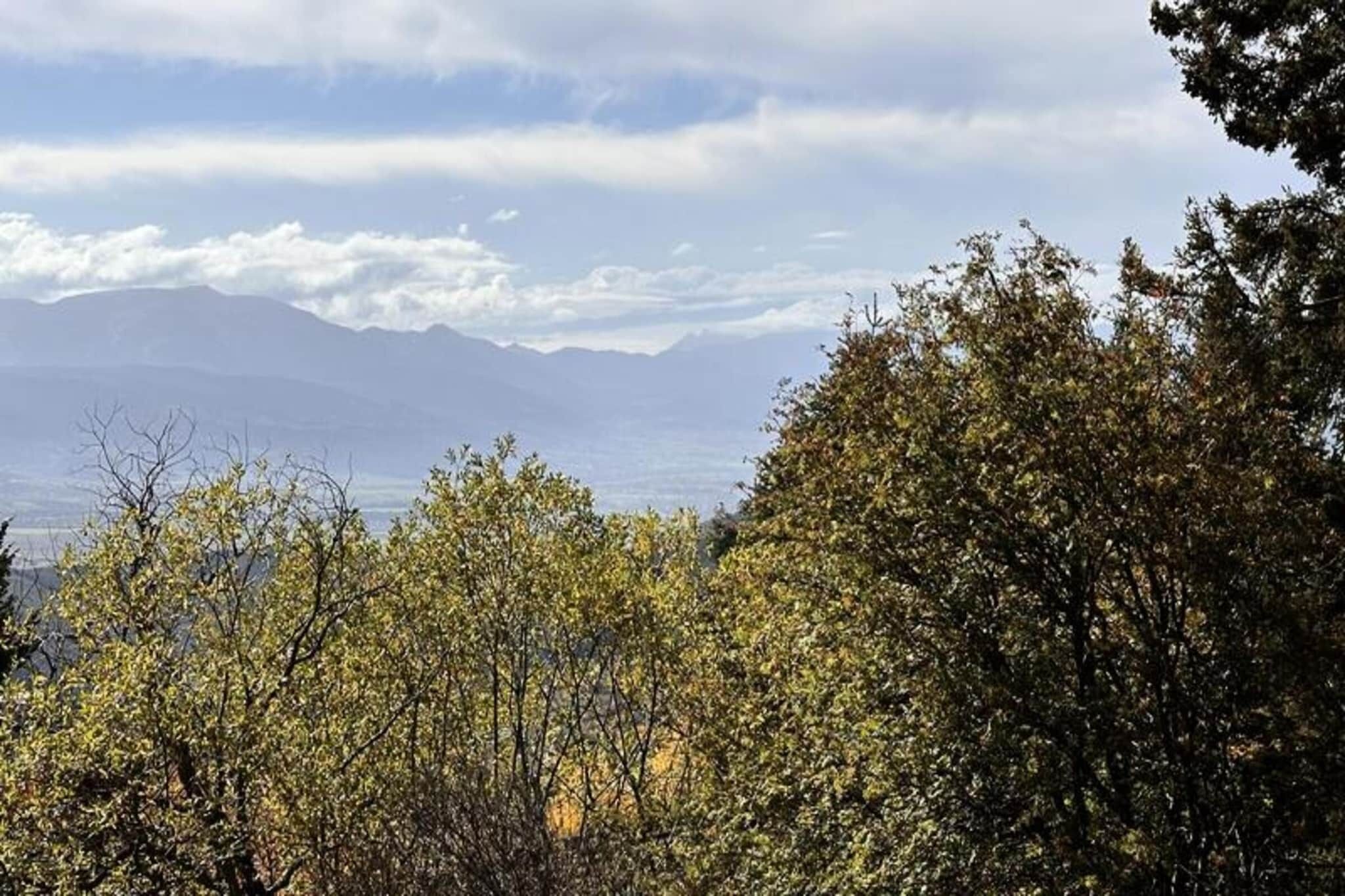 Un paysage montagneux, avec une végétation luxuriante au premier plan et des montagnes lointaines sous un ciel partiellement nuageux.