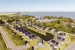Ett flygbildsbild av ett bostadsområde med hus som är placerade runt en central vattenyta och som är förbundna med varandra genom gångvägar.