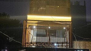Un edificio de varios pisos con un balcón en la planta baja, iluminado por una luz cálida.