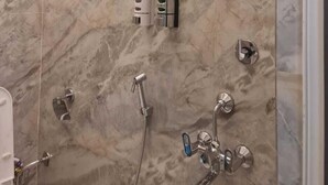 Un baño moderno con pared de mármol, cabezal de ducha manual y barra para toallas.